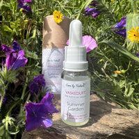 Summergarden vaskeduft står på en sten med sommerblomster omkring sig