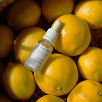 care by nature vaskeduft lemon breeze i klar glasflaske ovenpå citroner i flettet kurv med naturligt sollys og skygger